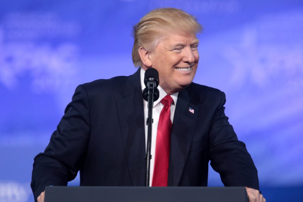 Donald Trump at a conference in front of a microphone with a big smile
