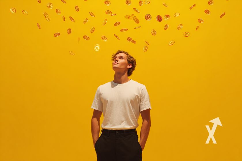 Homem com camiseta branca em fundo laranja com pequenos bitcoins acima dele.